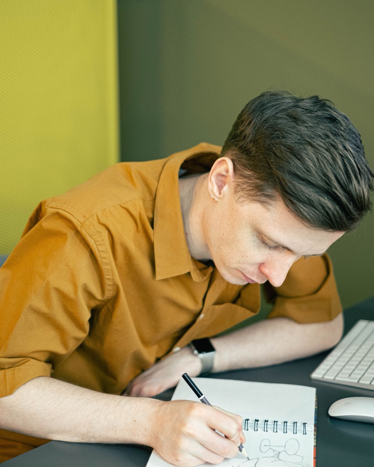 A student sketching at a desk during an online design class